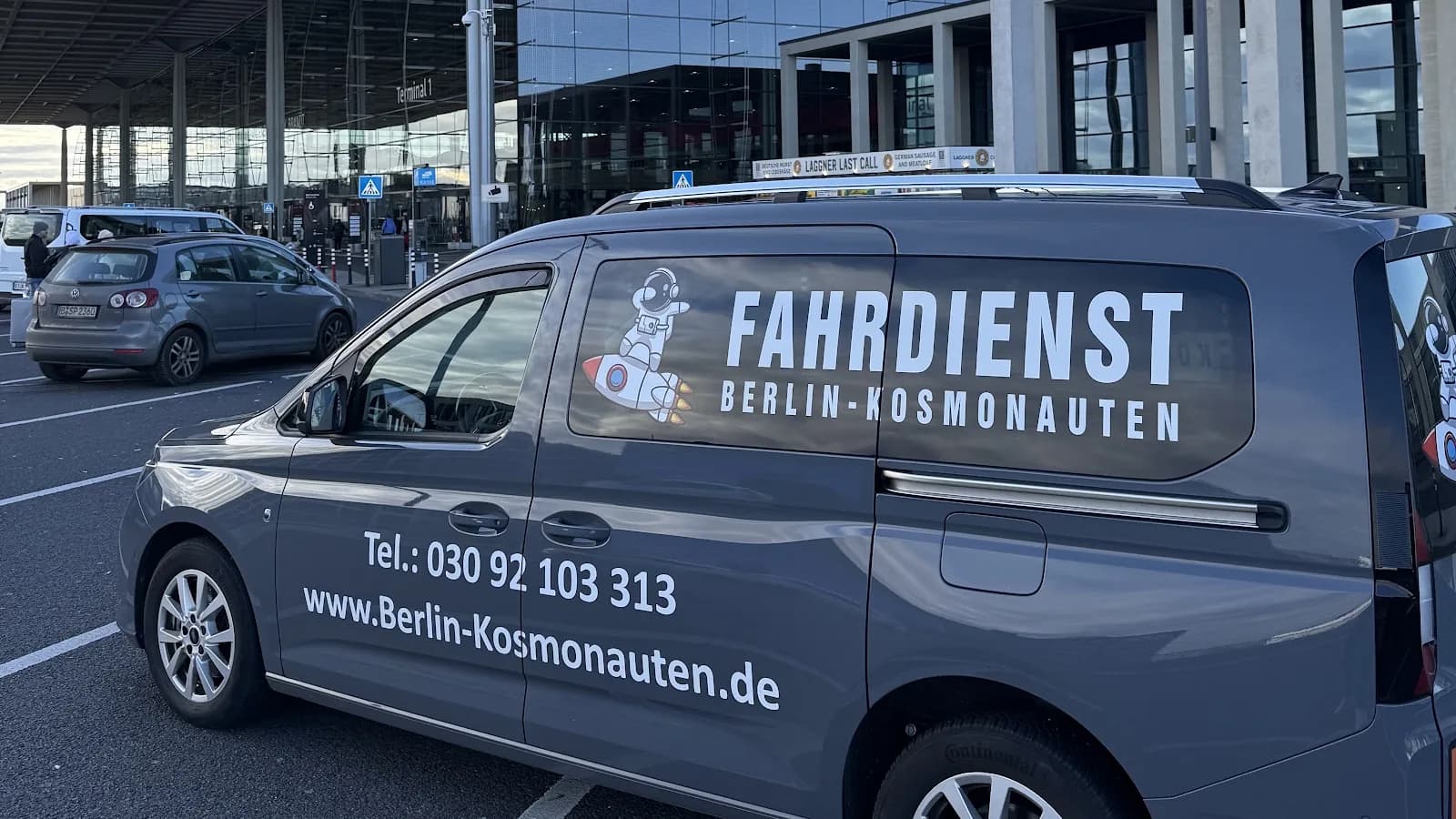 Kleinbus vom Fahrdienst Berlin-Kosmonauten vor dem Terminal des Flughafens BER