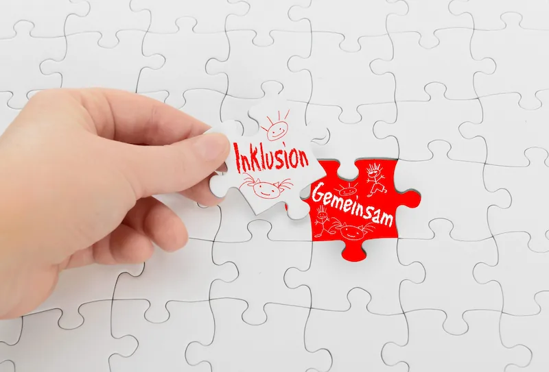 Hand hält Puzzleteil für Inklusion