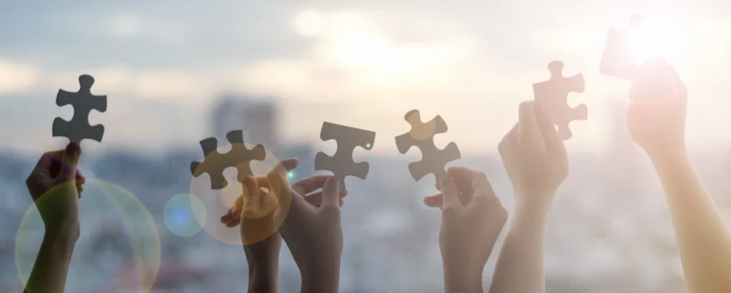 Hände von Kindern, die Puzzleteile als Symbol für Autismus oder Teamarbeit in der Schule zusammenhalten